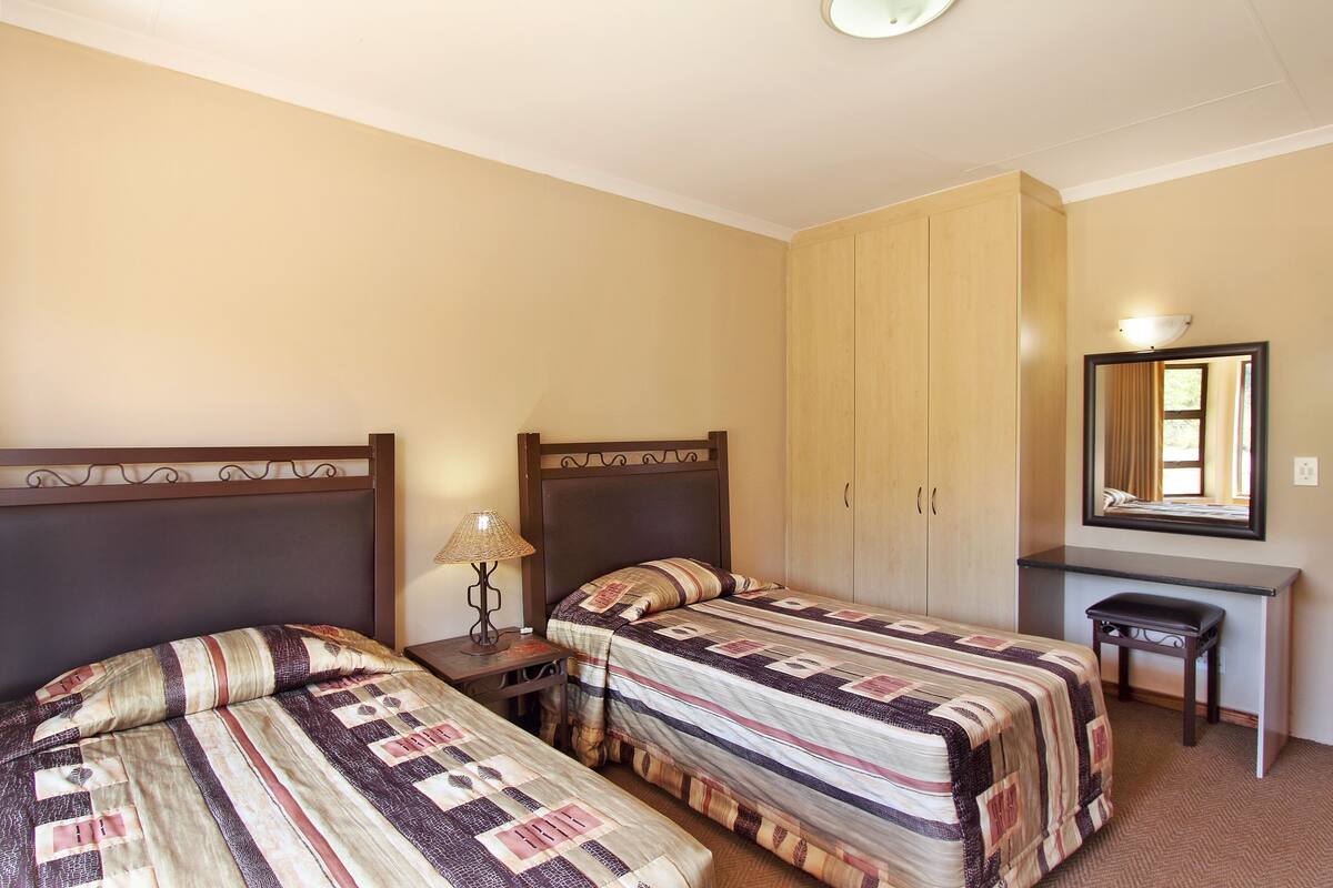 A bedroom with two beds, a desk, and a wardrobe.