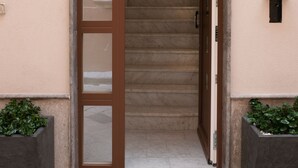 A building entrance with a wooden door, a staircase leading inside, and a number '8' sign on the wall. - San Francesco Rooms L.T. (Palermo)