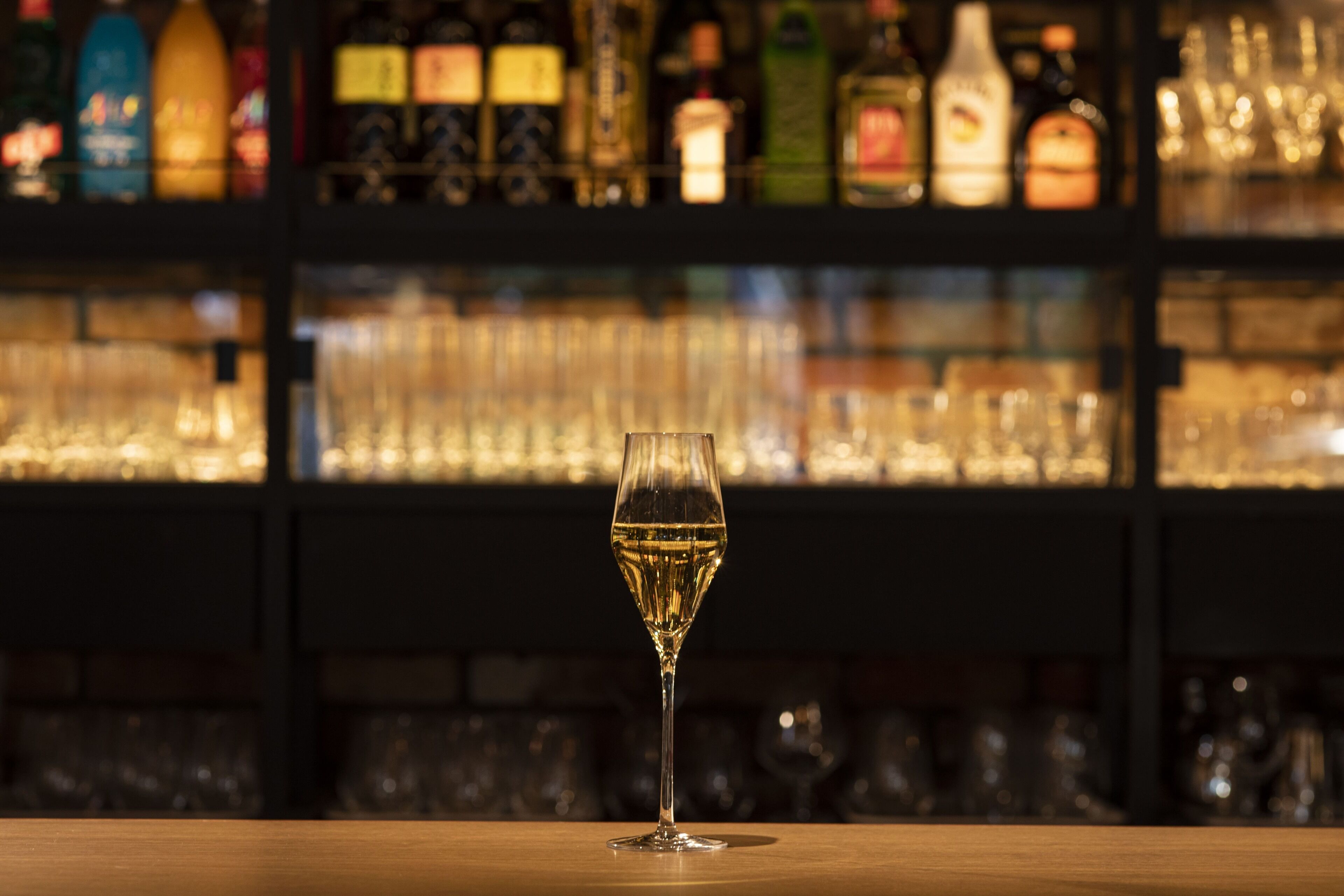 A bar with a glass of white wine on the counter.