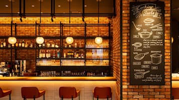 A bar area with a brick wall, shelves with bottles, glasses, and a chalkboard menu listing cooking tools.