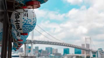 A view of a cityscape with a bridge and water, and traditional lanterns hanging.