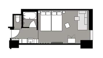 A hotel room layout with a bed, a small desk, a sofa, a bathroom, and a kitchenette.