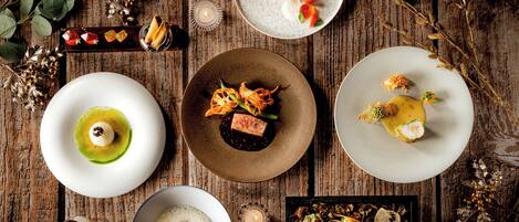 A variety of dishes on wooden tables with candles and greenery.