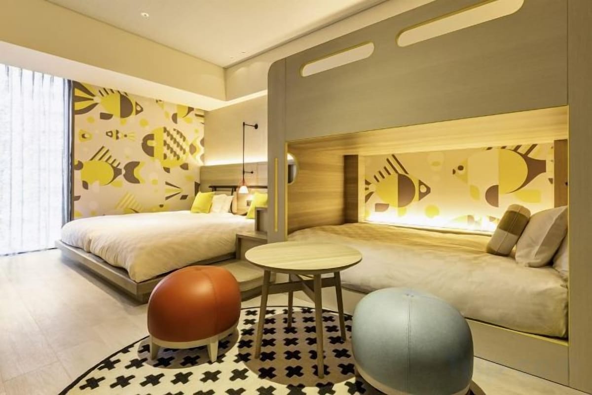 A hotel room with a bed, a sofa, a small table, and exercise balls.