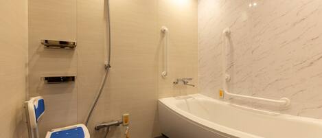 A bathroom with a white bathtub, a shower with a handheld showerhead, a grab bar, and a wheelchair-accessible seat.