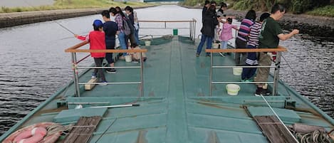 A boat with passengers fishing, equipped with life rings and a net.
