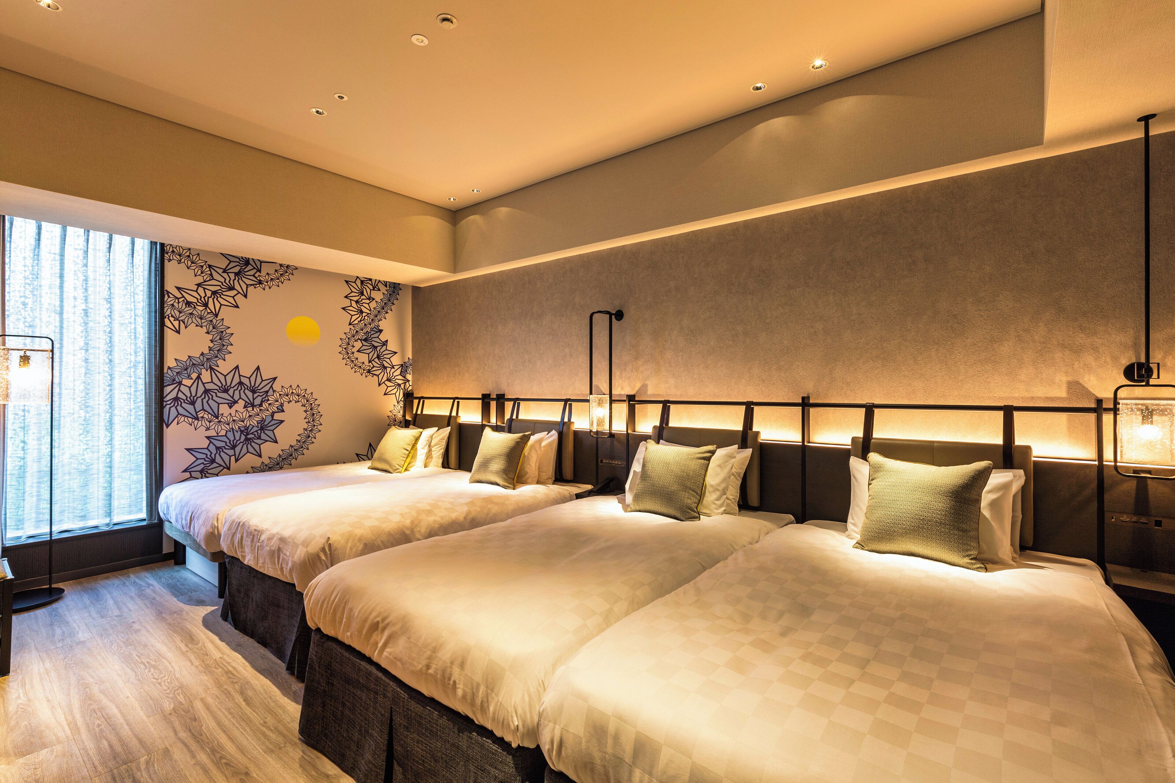 A hotel room with two beds, a large window with curtains, a wall mural, and a nightstand with a lamp.