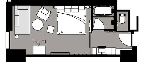 A hotel room layout with a bed, seating area, bathroom, and kitchenette.