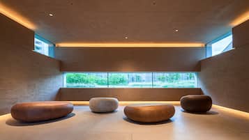A modern interior with four round seating areas, a large window with a view of greenery, and a ceiling with recessed lighting.