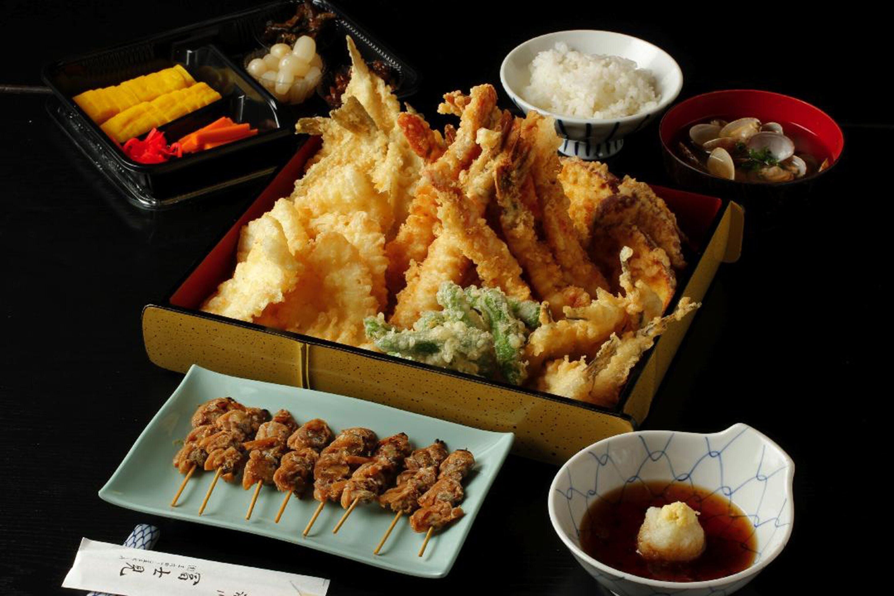 Variedad de platos japoneses, como tempura, brochetas y arroz.