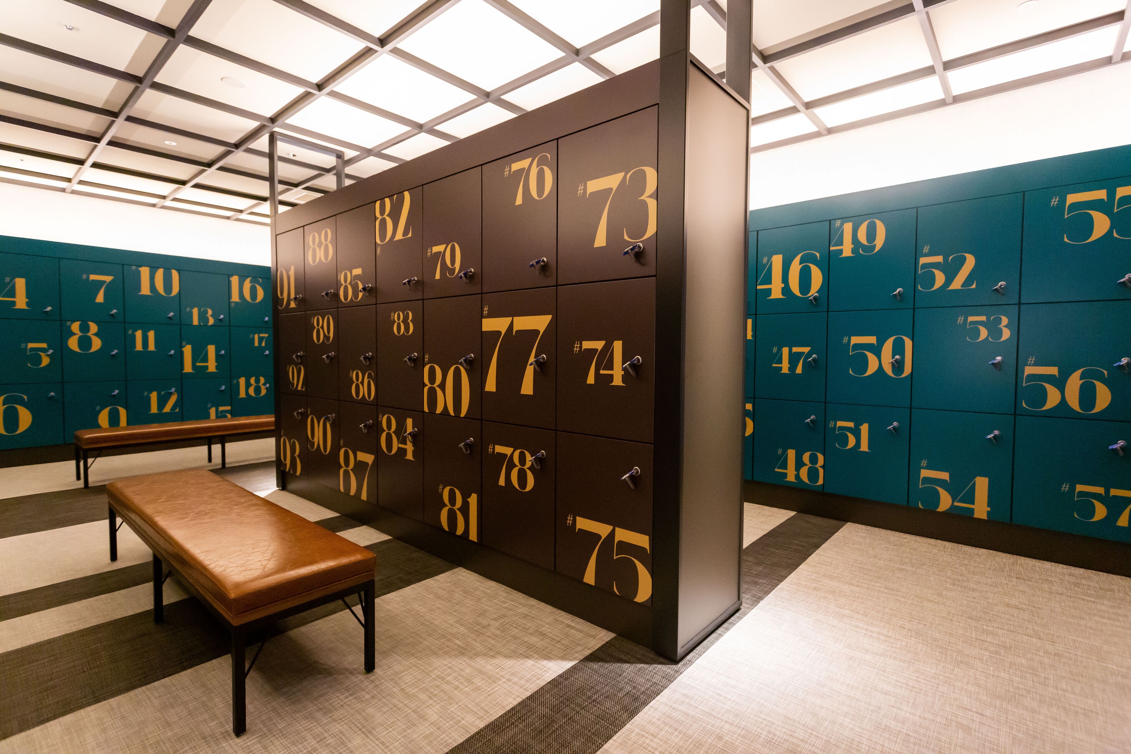 A locker room with numbered lockers and a bench.