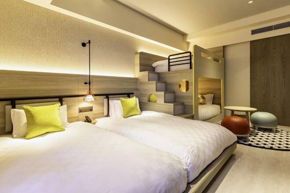A modern hotel room with a large bed, a built-in bench, a small table, and a unique circular seating area.