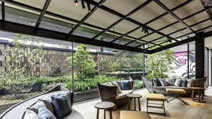 A modern outdoor seating area with a curved sofa, round tables, and a bench. - Tokyo Bay Shiomi Prince Hotel (Tokyo)