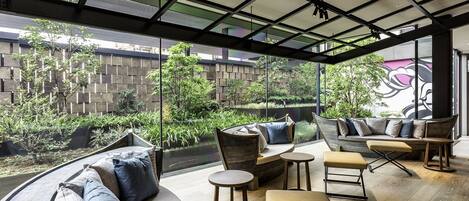 Un área de estar exterior moderna con un sofá curvo, mesas redondas y un banco.