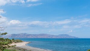 A coastal landscape with a clear sky, a sandy beach, and distant mountains. - Musela Studios (Rethymno)