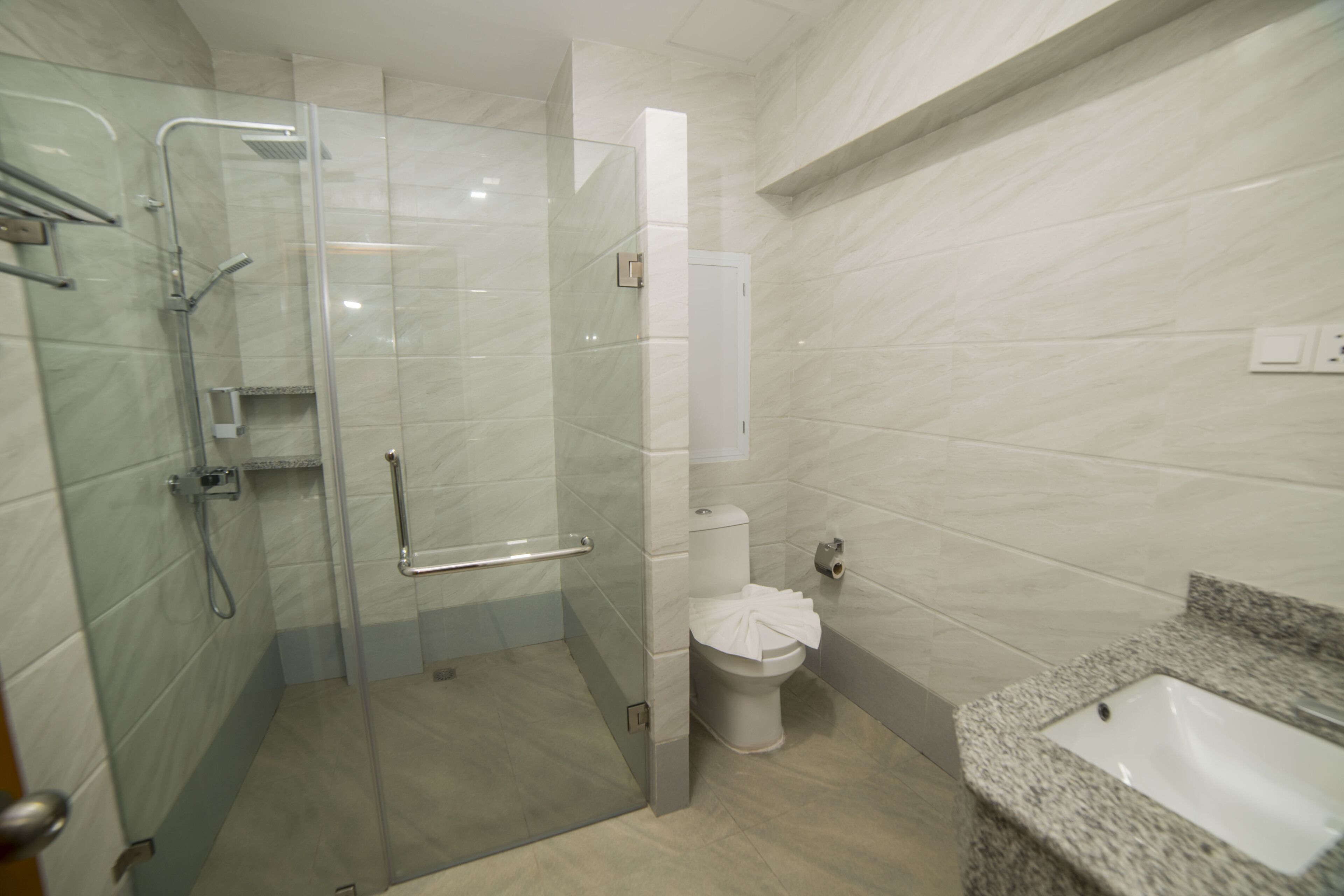 Un baño moderno con ducha de vidrio, inodoro y lavamanos de granito.