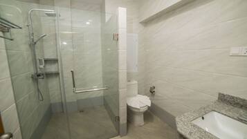 Un baño moderno con ducha de vidrio, inodoro y lavamanos de granito.