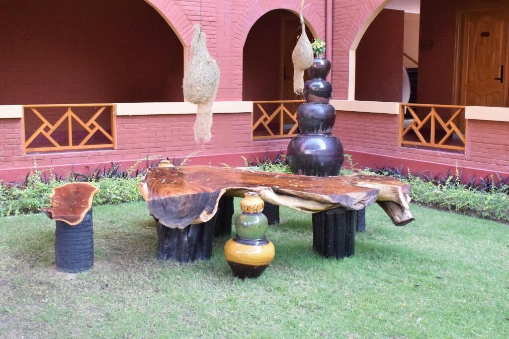 A courtyard with a wooden table, vases, and hanging decorations against a red brick wall with arched windows.