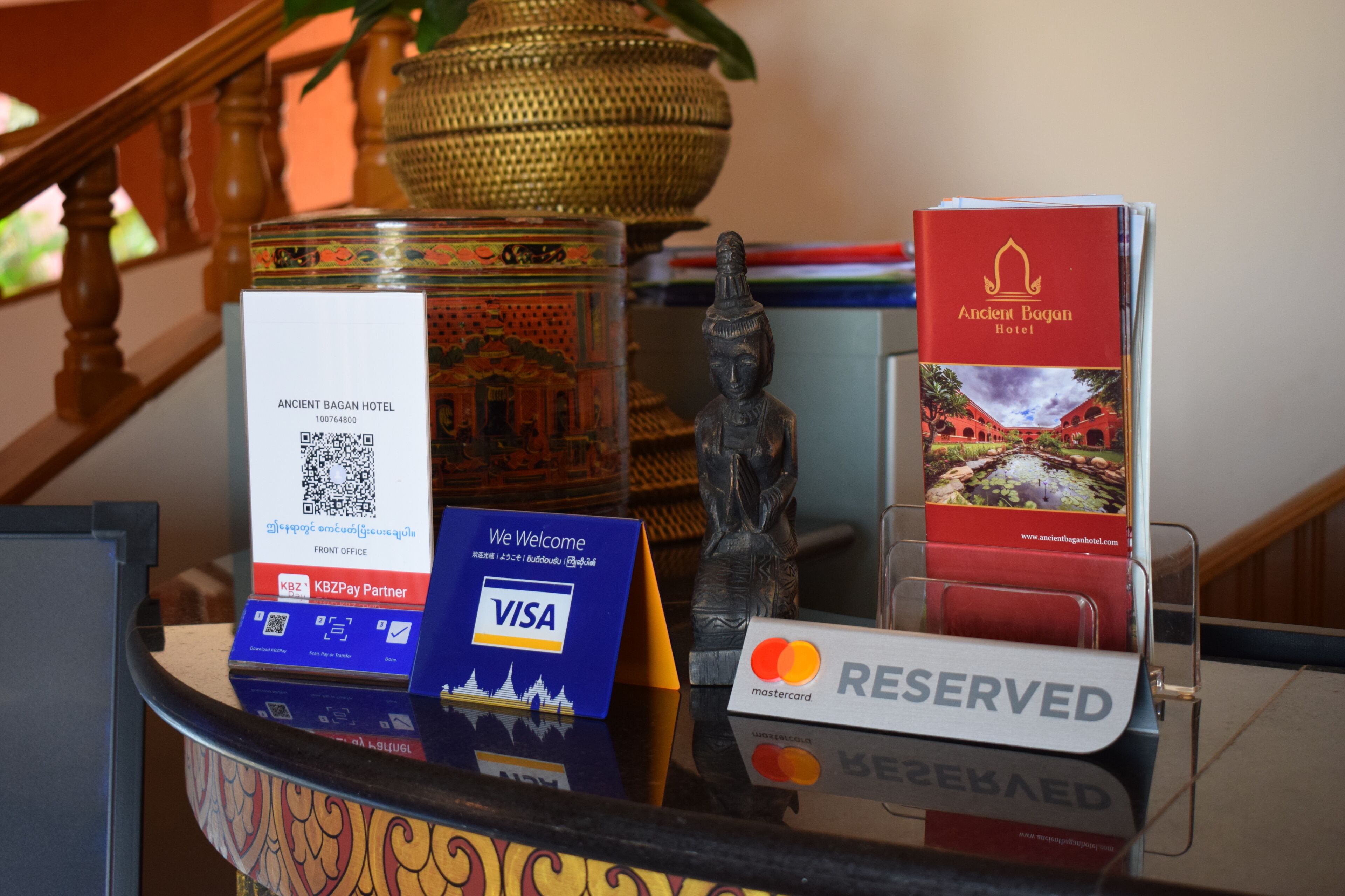 A reception desk with a QR code, a statue, a brochure, and a 'RESERVED' sign.