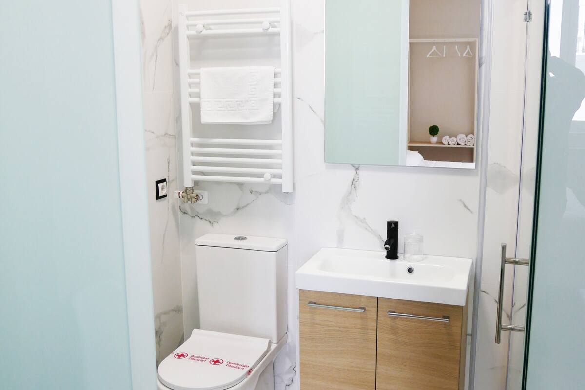 A bathroom with a toilet, sink, and mirror.