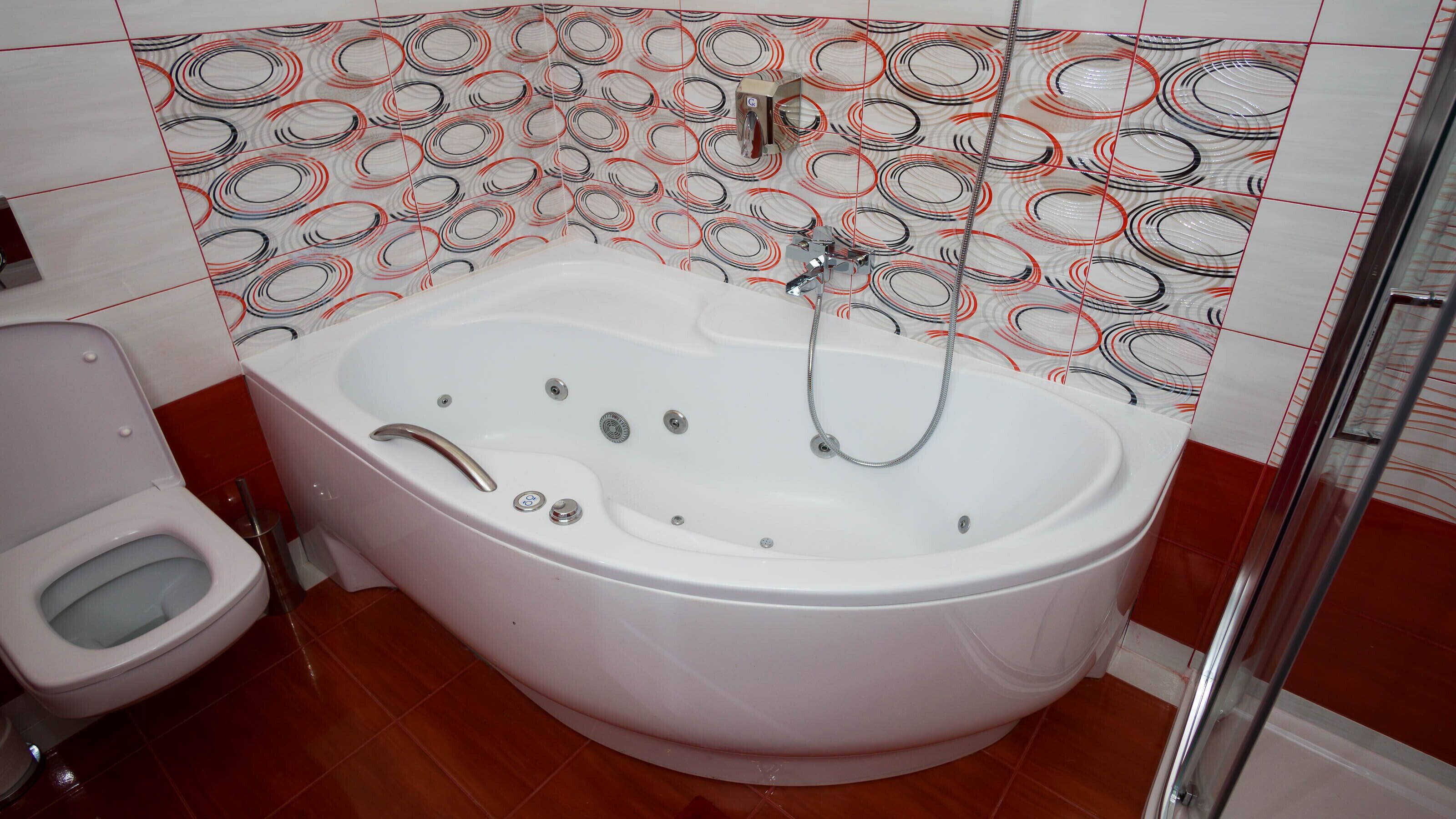 A bathroom with a large bathtub, a toilet, and a shower area.