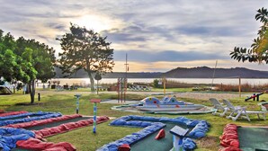 A park with a boat-shaped play structure, a tennis court, and a grassy area with colorful mats. - Baywater Village (Sedgefield)
