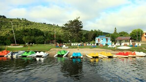 A lakeside area with boats docked, a small building, and a hill in the background. - Baywater Village (Sedgefield)