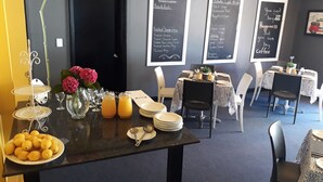 A breakfast setup with a menu board, a table with plates, lemons, and a vase of flowers. - Baywater Village (Sedgefield)