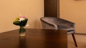 Ein Holztisch mit Blumen in einer Vase und ein grauer Stoffstuhl.