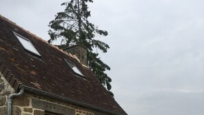 Ein Haus aus Stein mit einem Ziegeldach, einer Holzterrasse und einem Tisch mit Stühlen.