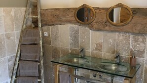 Ein Badezimmer mit Waschbecken aus Glas, einer Holzleiter und zwei Wandspiegeln.