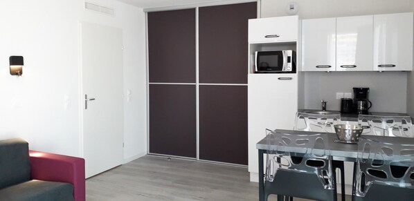 Una cocina moderna con microondas, cafetera y un comedor con taburetes.