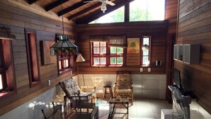 A cozy cabin-style room with a dining table, chairs, a sofa, and a TV. - Lagoa Country Club (Cidreira)