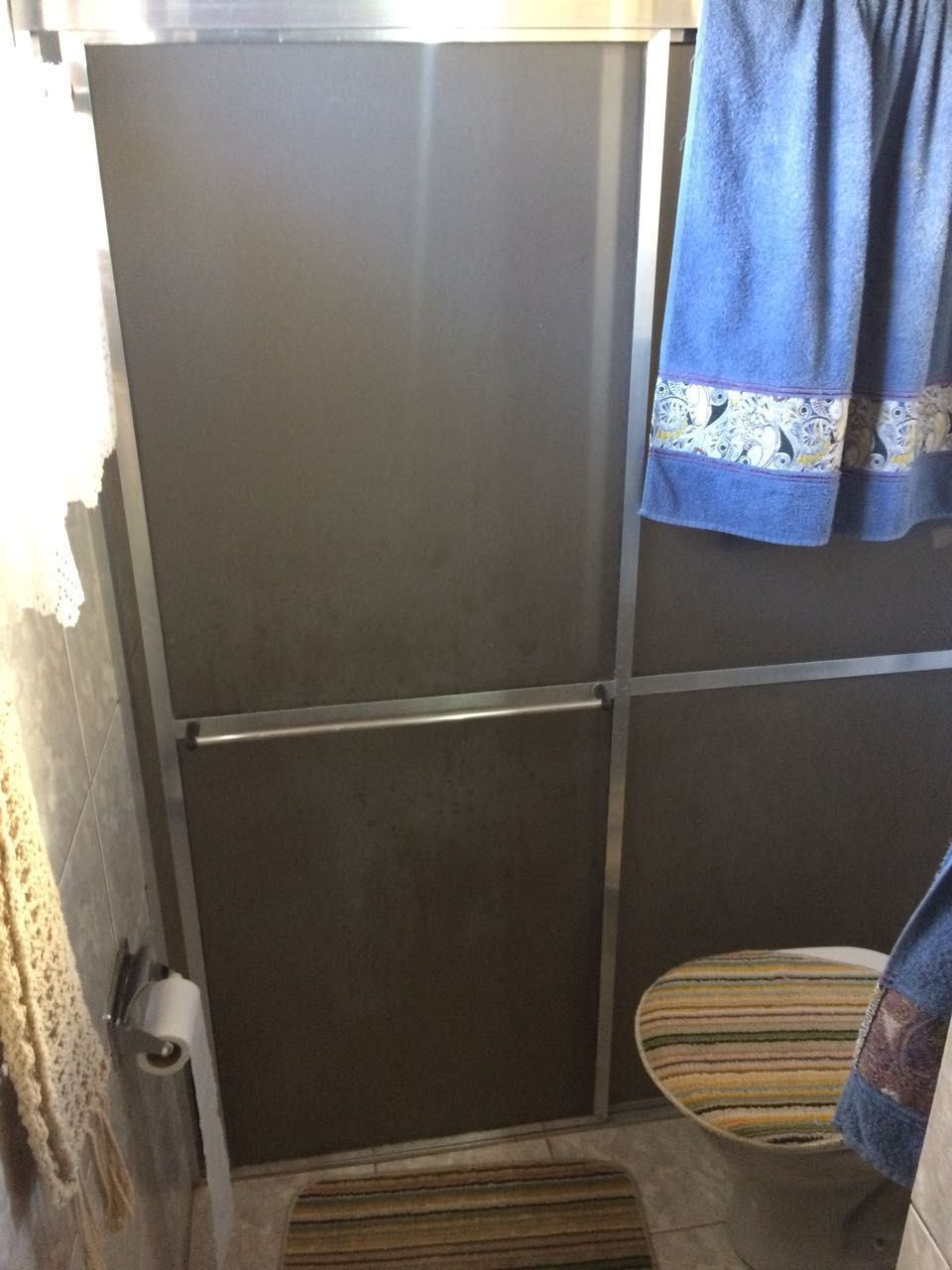 Un baño con cabina de ducha, inodoro y una toalla colgada en la pared.