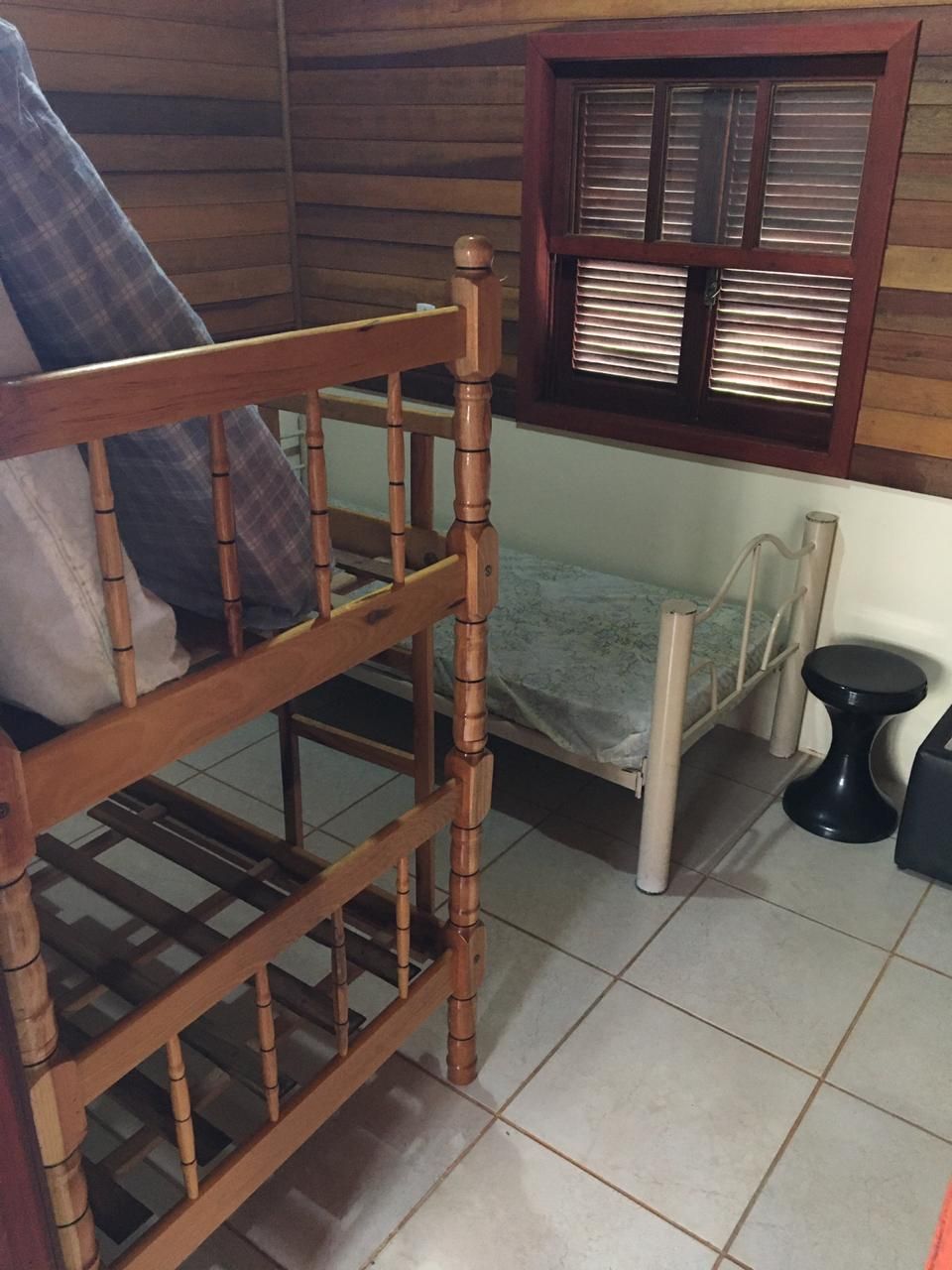 A wooden bunk bed with a mattress and a small table beside it.