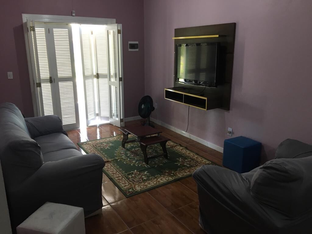 Een woonkamer met een bank, een salontafel, een aan de muur bevestigde televisie en een schuifdeur.
