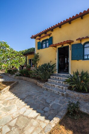 A yellow building with a stone pathway leading to a wooden door. - Gorgeous Stone Cottage by the sea (Chania)