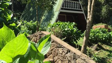 A garden with a stone pathway leading to a green-roofed structure with a white balcony.