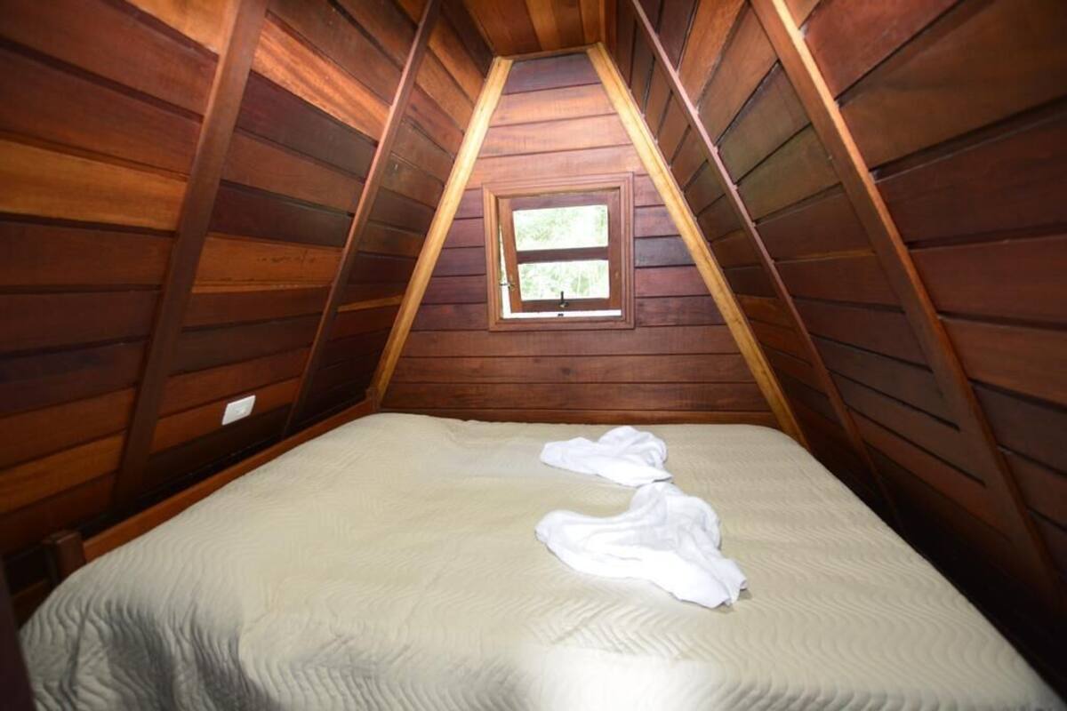 Ein kleines Zimmer mit schrägem Dach, einem Bett und einem Fenster.