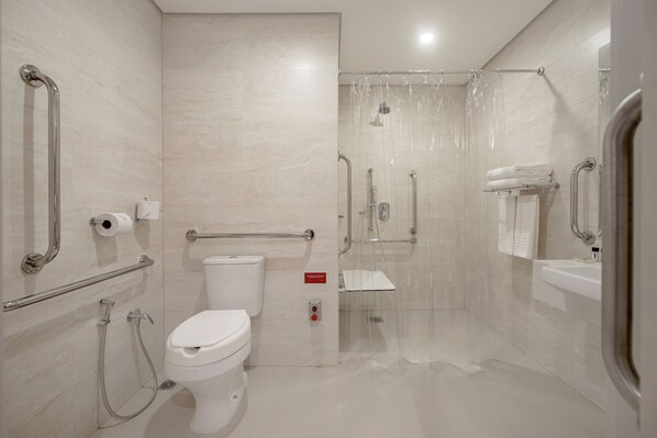 Un baño moderno con inodoro, ducha y barras de apoyo.