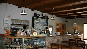 A rustic bar area with wooden beams, a stone counter, and shelves stocked with bottles and glasses. - Auberge de la Foret (Calenzana)