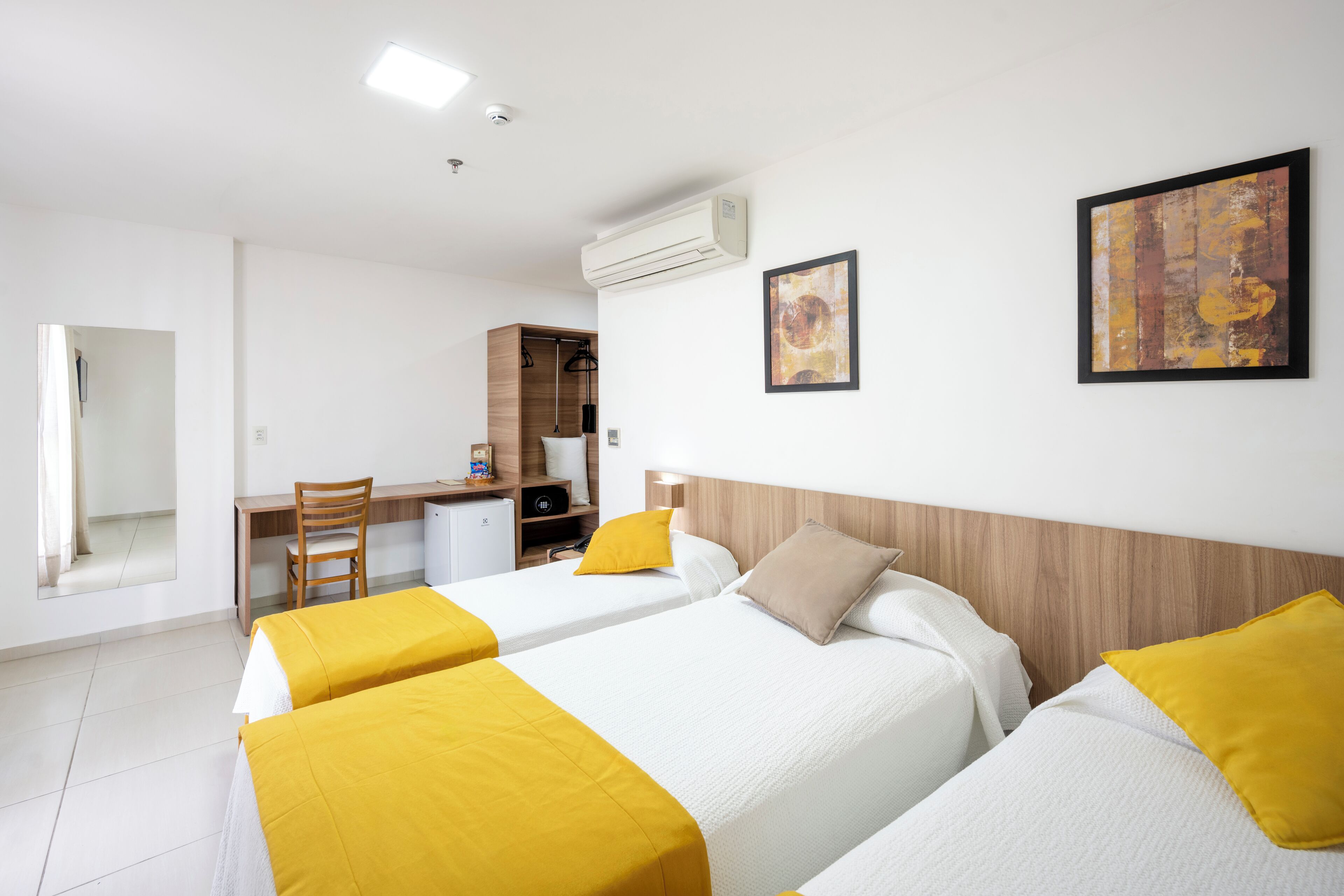 Una habitación de hotel con dos camas, un escritorio, una silla y un armario.