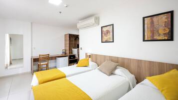Una habitación de hotel con dos camas, un escritorio, una silla y un armario.