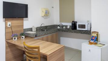 Cocina compacta con mostrador de madera, pileta, microondas, cafetera y refrigerador pequeño.