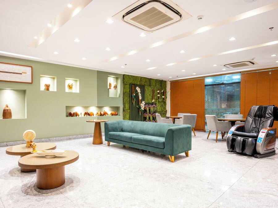 Un área de recepción moderna con un sofá color turquesa, sillón de masaje y mesas redondas.