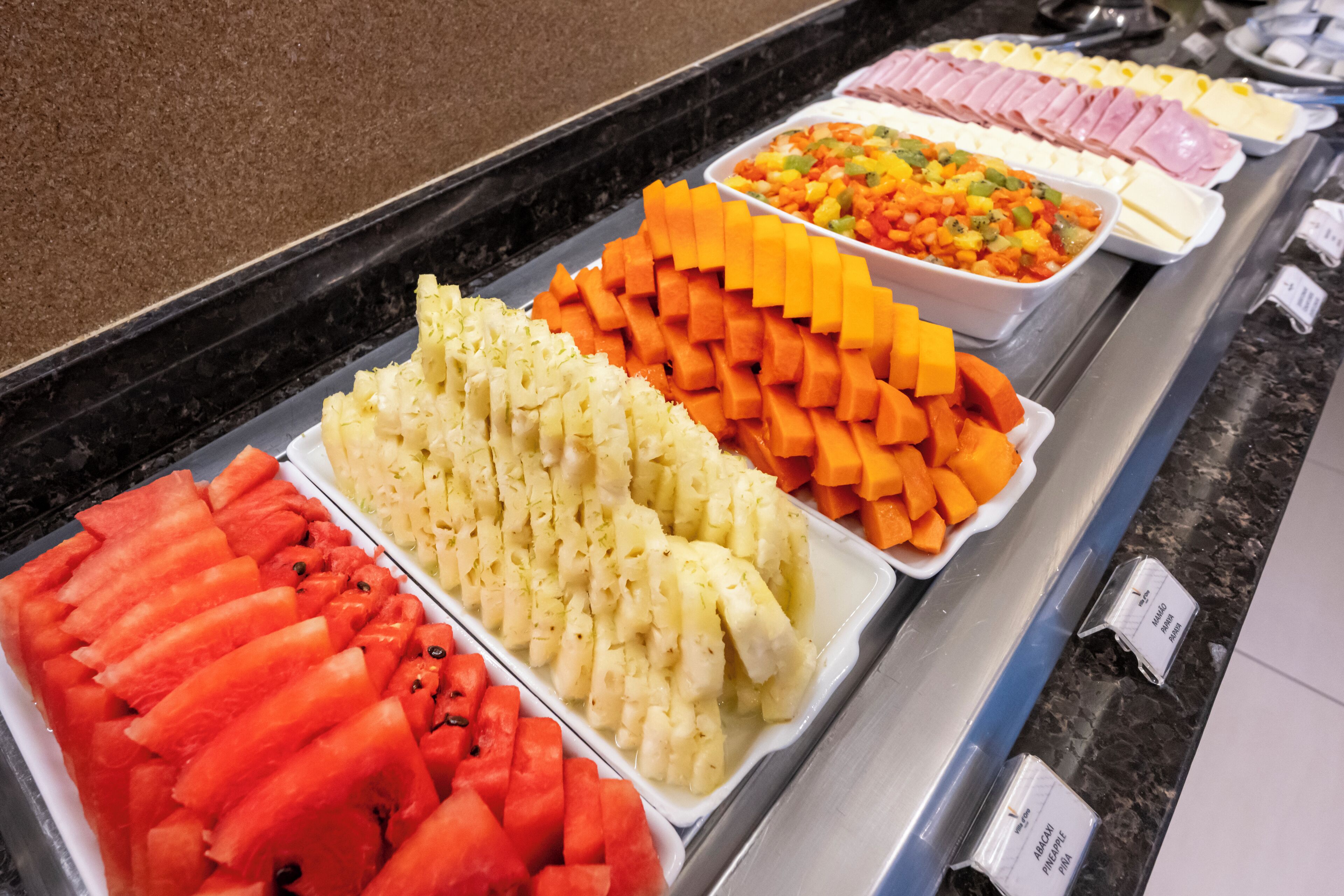 Buffet com diversas opções de comida, incluindo frutas e carnes.