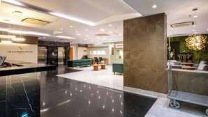Un moderno vestíbulo de hotel con mostrador de recepción, área de estar y una pared verde con textura.