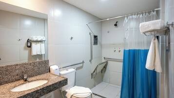 Ein modernes Badezimmer mit Marmorwaschtisch, Toilette, Dusche mit Glastür und blauer Duschvorhang.
