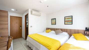 A hotel room with two beds, a wooden wardrobe, a desk, and a telephone.