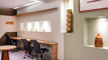 A modern reception area with a wooden desk, black office chairs, and a 'Business Center' sign.